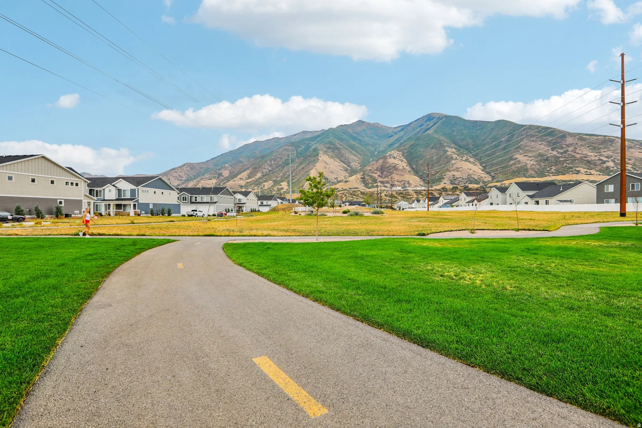Paved walking path bordered by manicured lawn and open green space