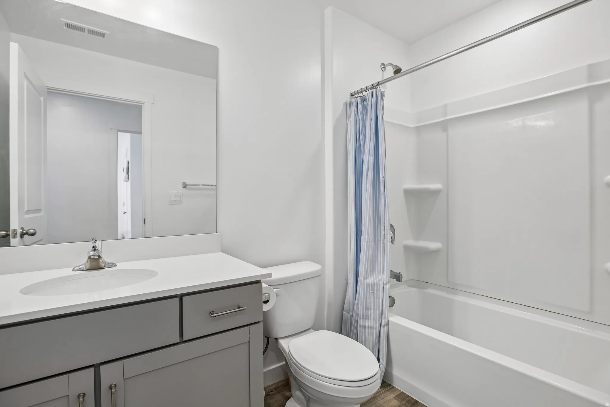 White vanity with a single basin sink, brushed nickel faucet, and a large wall-mounted mirror
