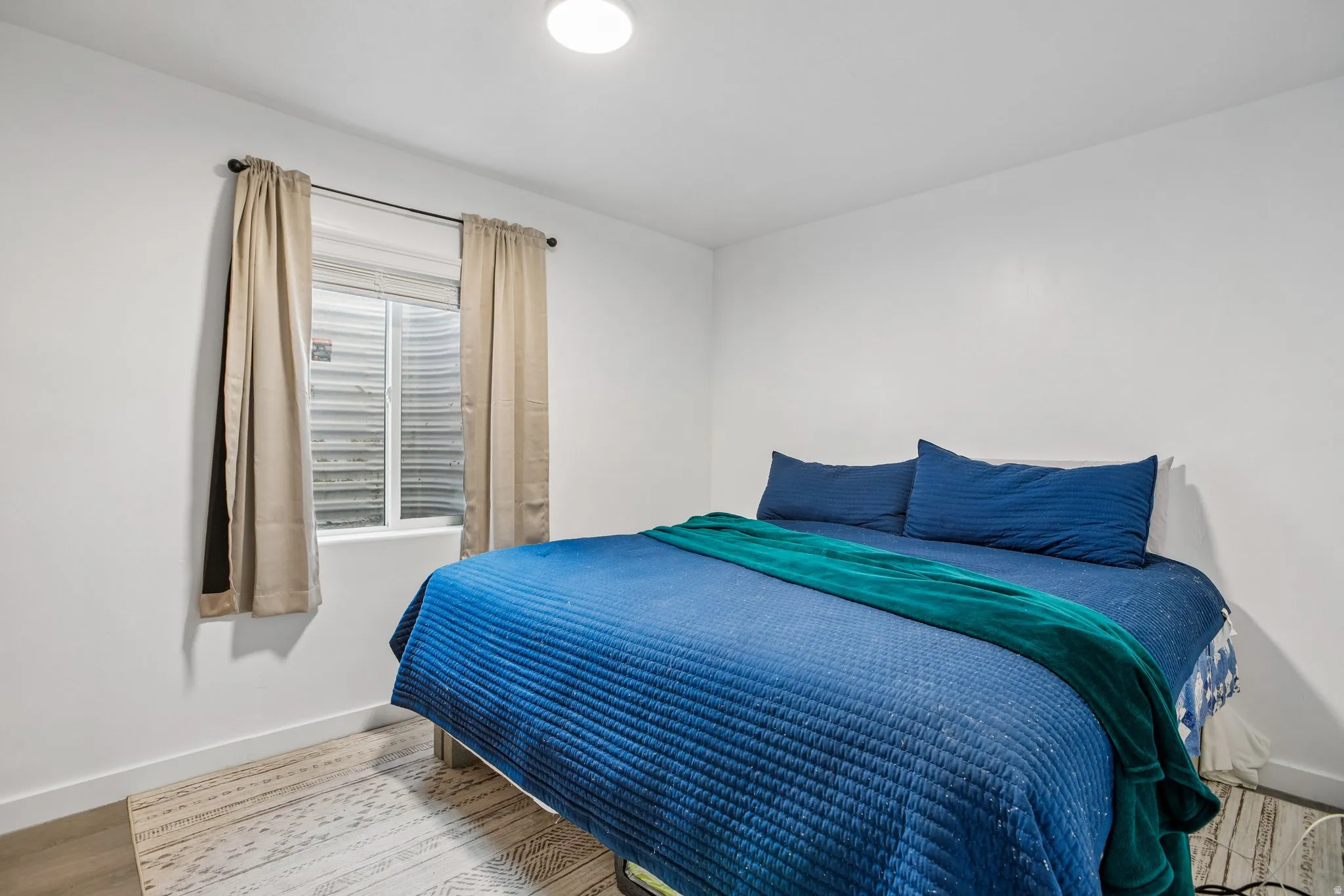 Recessed window with blinds, light-toned wall paint, and overhead flush-mount lighting