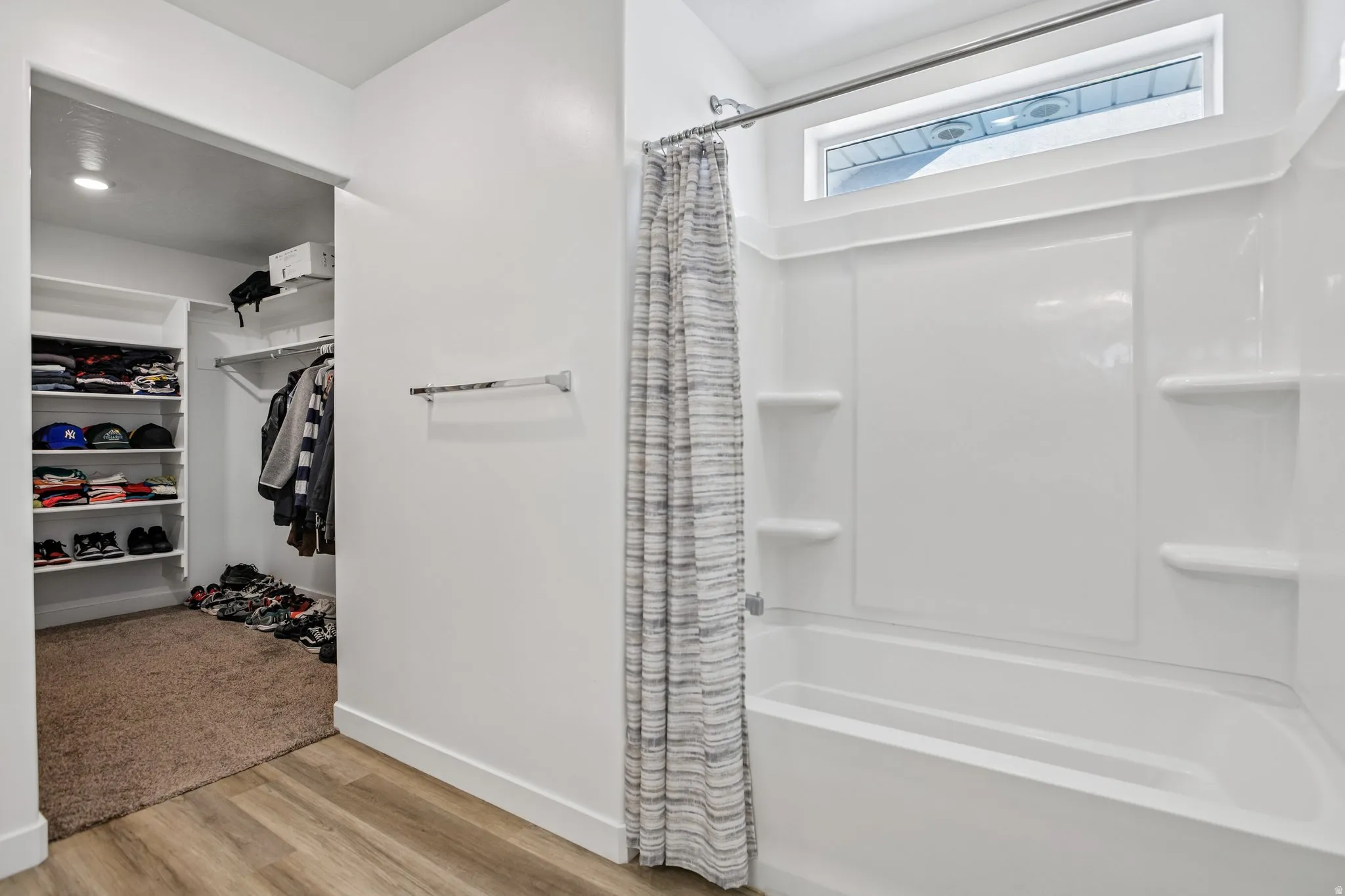 White tub and shower combination with an integrated shelving system and transom window