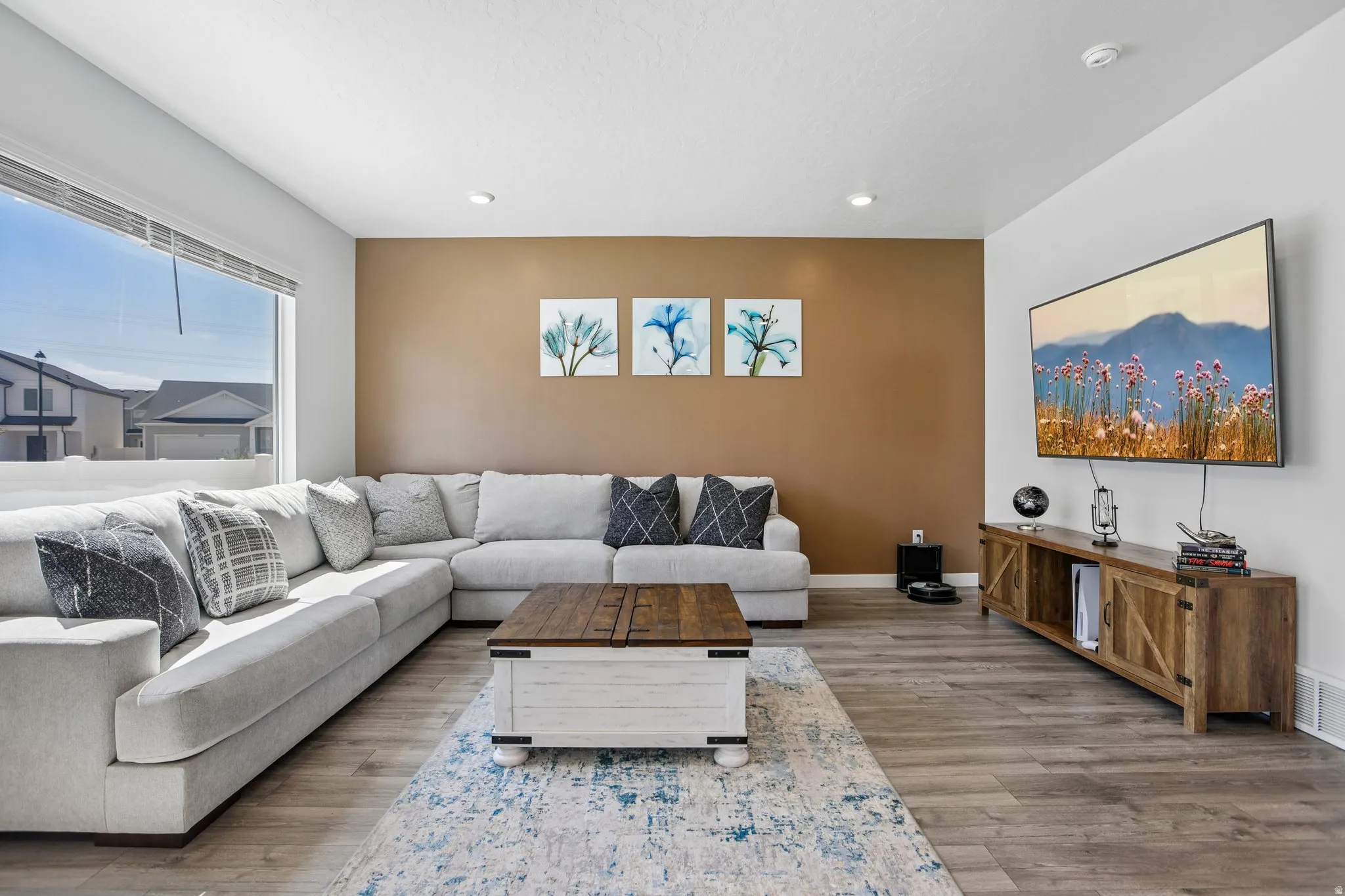 Expansive window providing ample natural light, wood-finish flooring, recessed ceiling lighting, and a feature accent wall