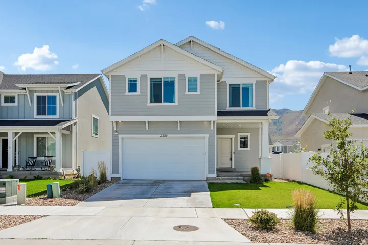 Two-story residence featuring light gray siding, white trim, an attached garage, a covered entry, and a concrete driveway