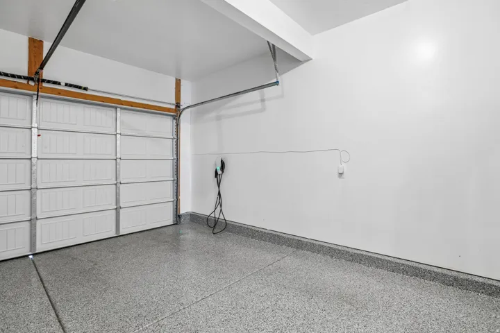 Garage with a white sectional door, grey speckled flooring, and an electric vehicle charging station