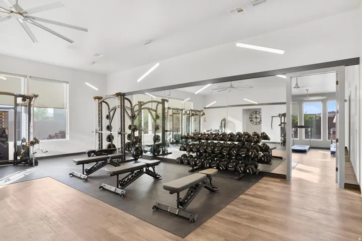 Fitness center with wood-finish flooring, ceiling fans, and expansive wall mirrors