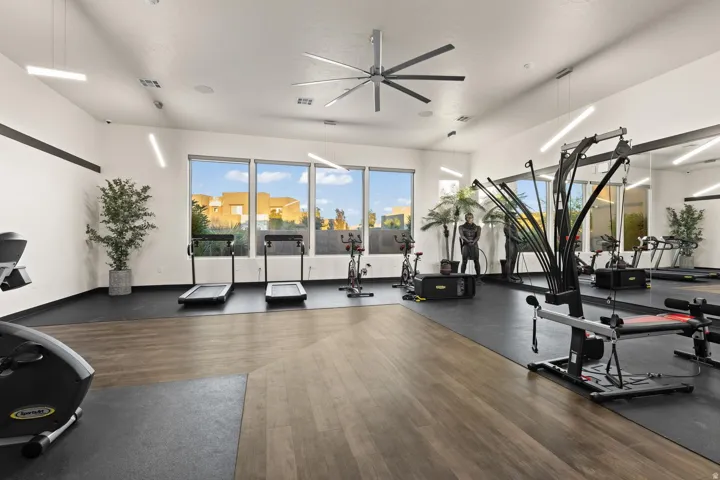 Fitness area featuring expansive windows, wood-finish flooring, recessed lighting, and a large ceiling fan