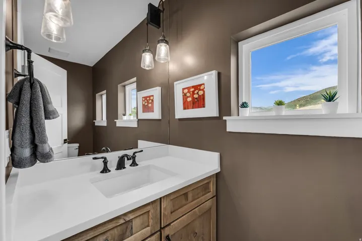Built-in vanity featuring a rectangular undermount sink, a white countertop, and wood-finish cabinetry