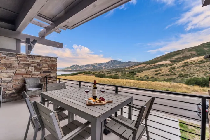 Expansive outdoor deck featuring a stone accent wall, wood pergola, and mountain scenery