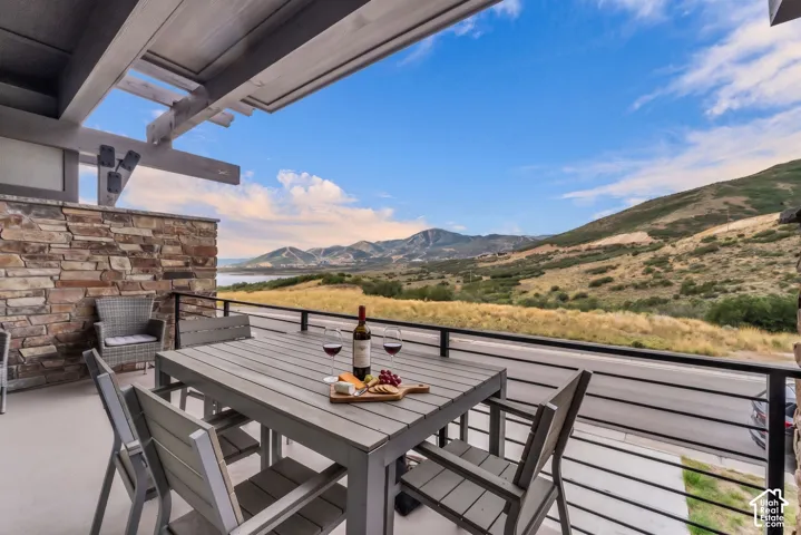 Expansive outdoor deck featuring a stone accent wall, wood pergola, and mountain scenery