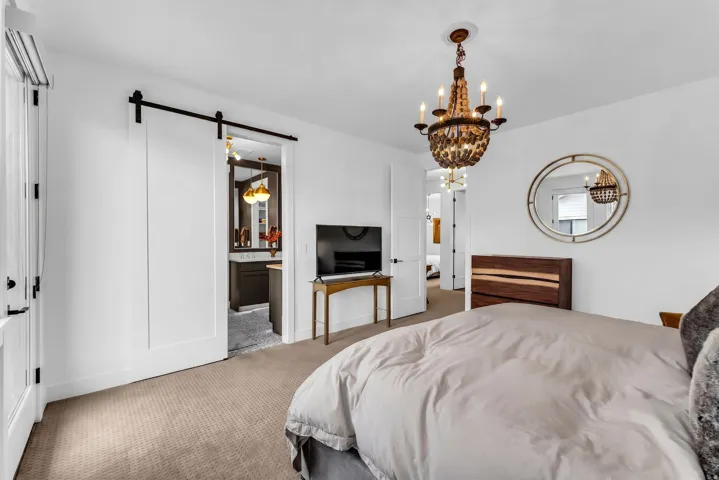 White walls, neutral carpet, and a decorative chandelier