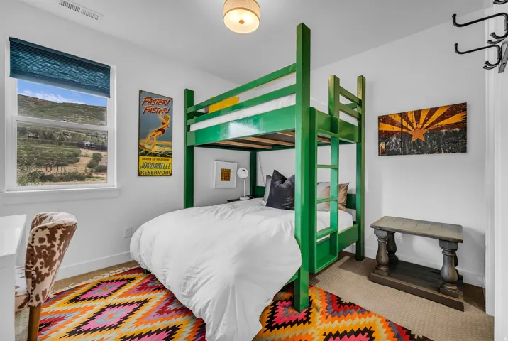 White walls with a single window, featuring a green bunk bed and neutral carpeting