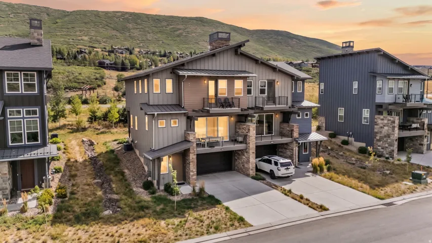 Multi-level contemporary exterior with board and batten siding, multiple balconies, an integrated garage, and a concrete driveway