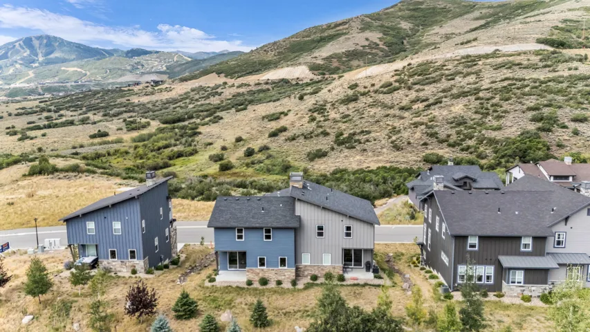 Contemporary architecture with vertical siding, stone accents, multiple windows, and a mountain backdrop