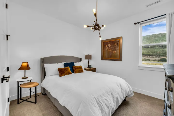 Recessed window with a mountain backdrop, modern chandelier, and upholstered headboard