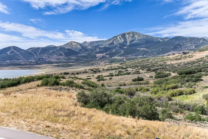Mountain landscape featuring a body of water, distant structures, and expansive natural terrain