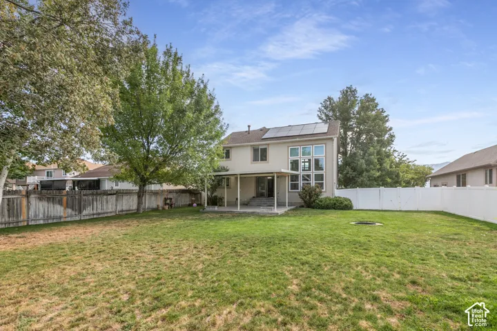 Expansive backyard with a manicured lawn, established trees, and a privacy fence