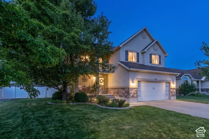 Stucco exterior with stone accent detailing, attached garage, and covered front porch