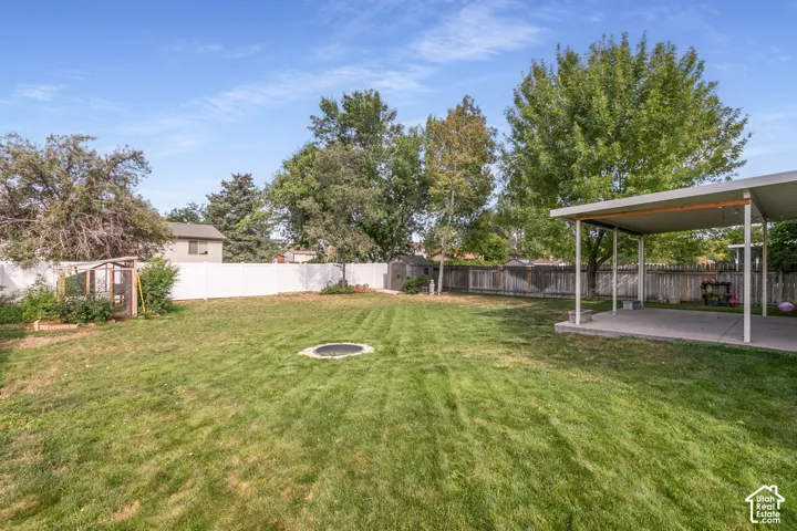 Expansive lawn area, covered patio structure, perimeter fencing, mature trees.