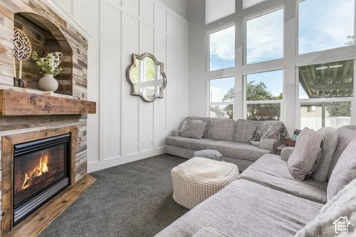 Stacked stone fireplace with a wood mantel, high ceilings, large multi-pane brand new windows, and board and batten wall detailing