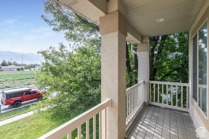Upper level covered balcony featuring composite decking, white railing, and stucco columns
