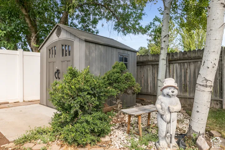 Wood-look storage shed with double doors and window and concrete pad at entrance.