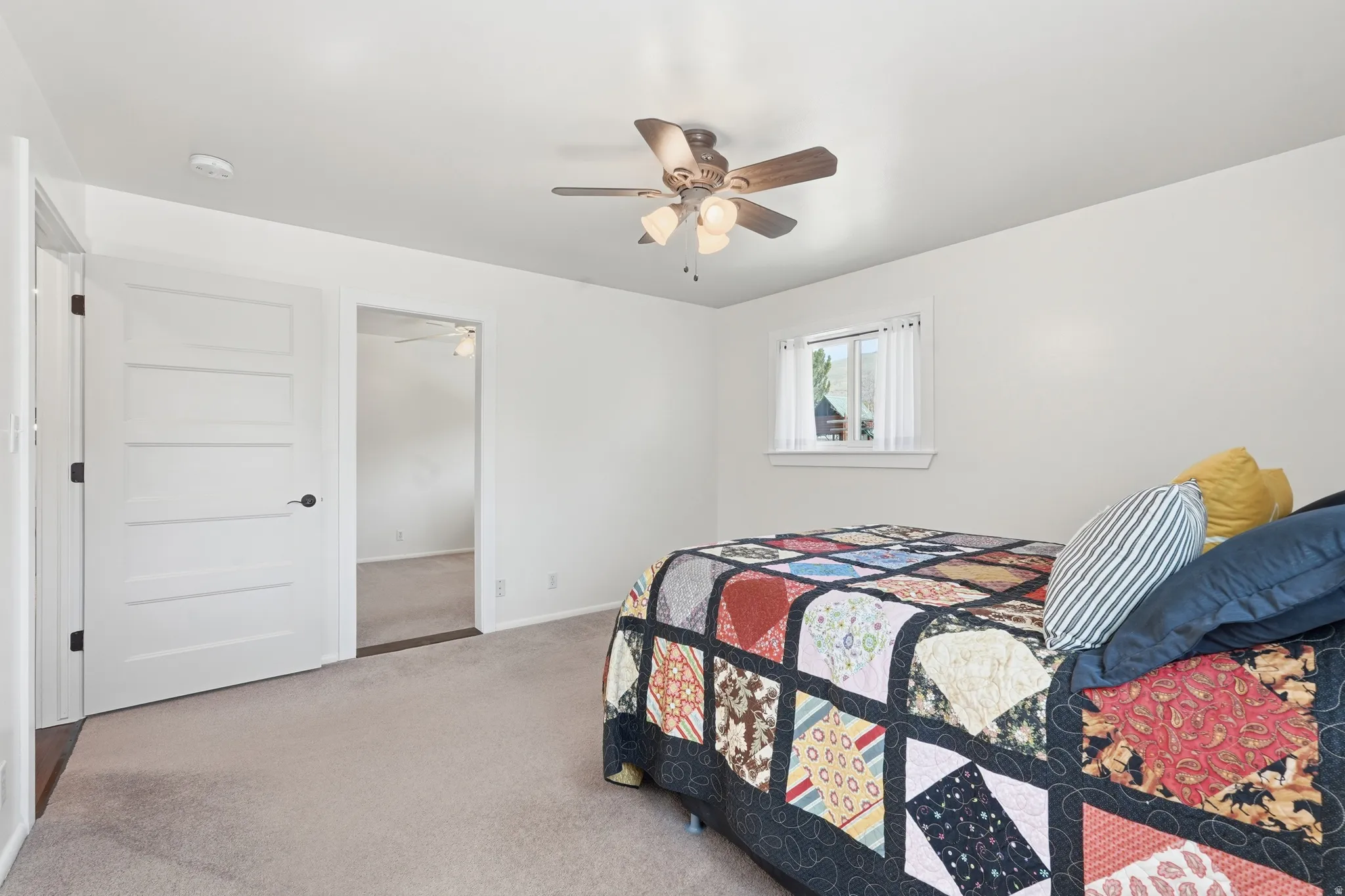 Recessed lighting, ceiling fan with light fixture, window with white trim, white interior doors with black hardware, and neutral carpeting