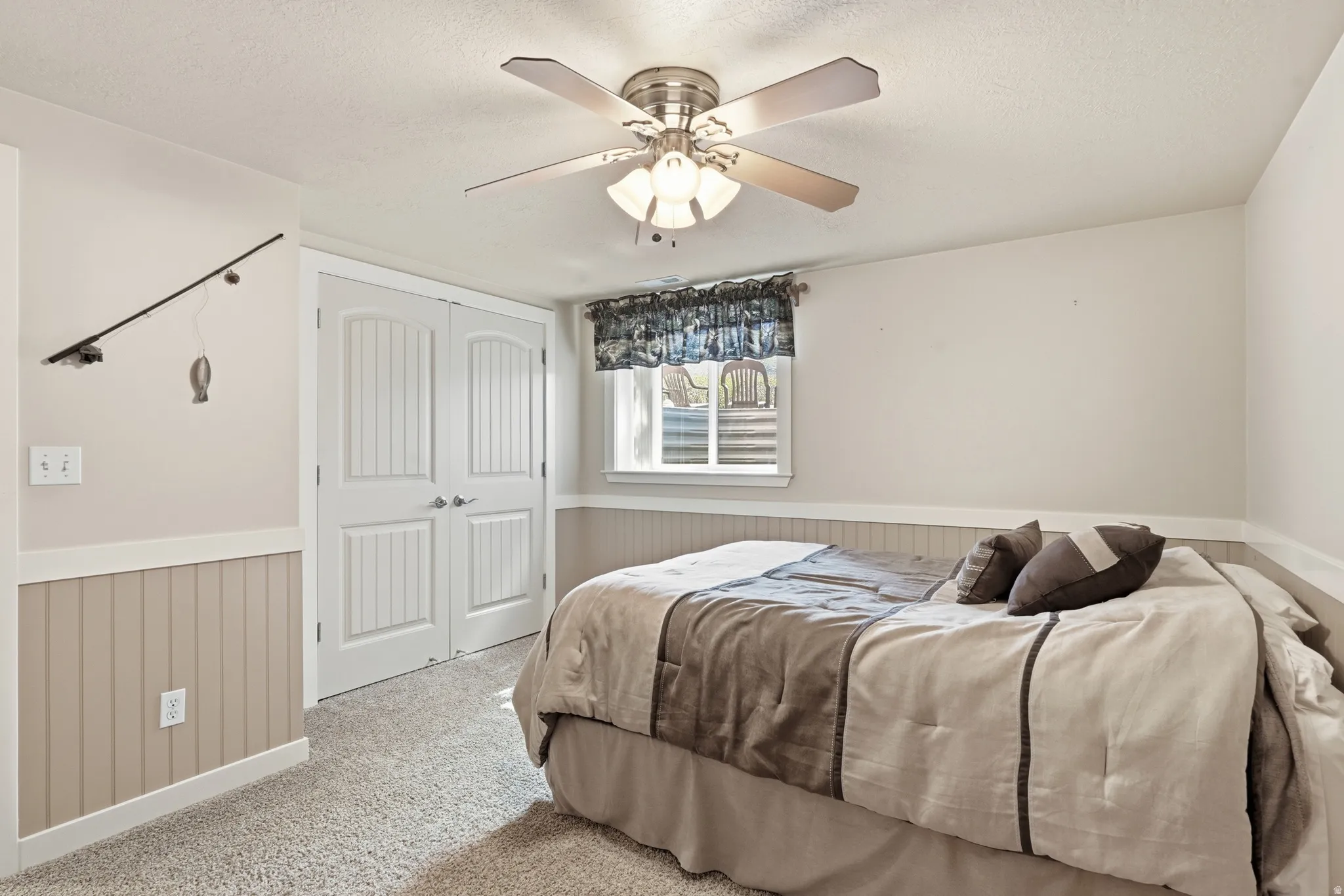 Neutral wall paint, ceiling fan with integrated lighting, window with trim, beadboard wainscoting, and carpeted flooring