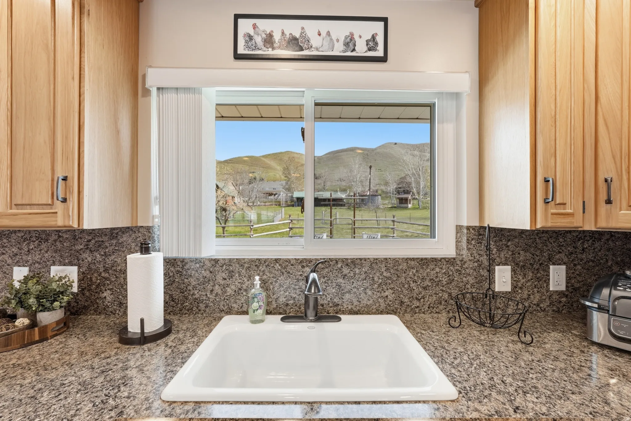 White single-basin sink with a stainless steel faucet, granite-finish countertops, and light wood cabinetry