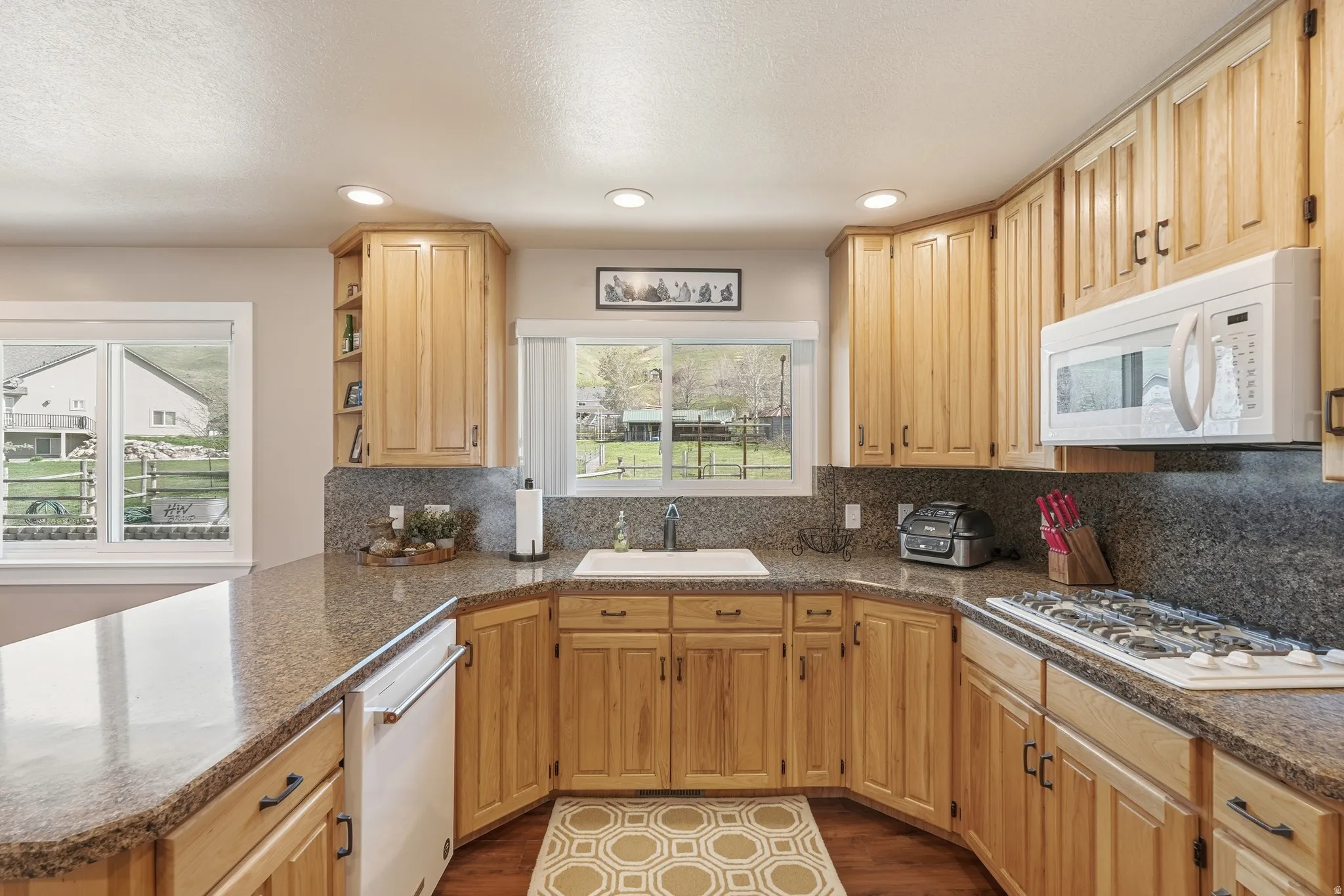 U-shaped kitchen featuring wood cabinetry, integrated gas range, built-in microwave, and solid surface countertops