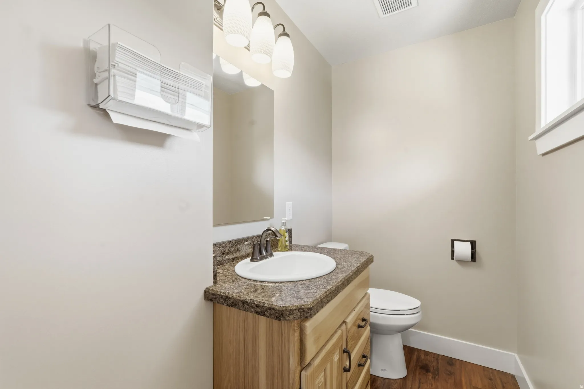 Wood-finish flooring with a vanity featuring a built-in sink and a complementary countertop