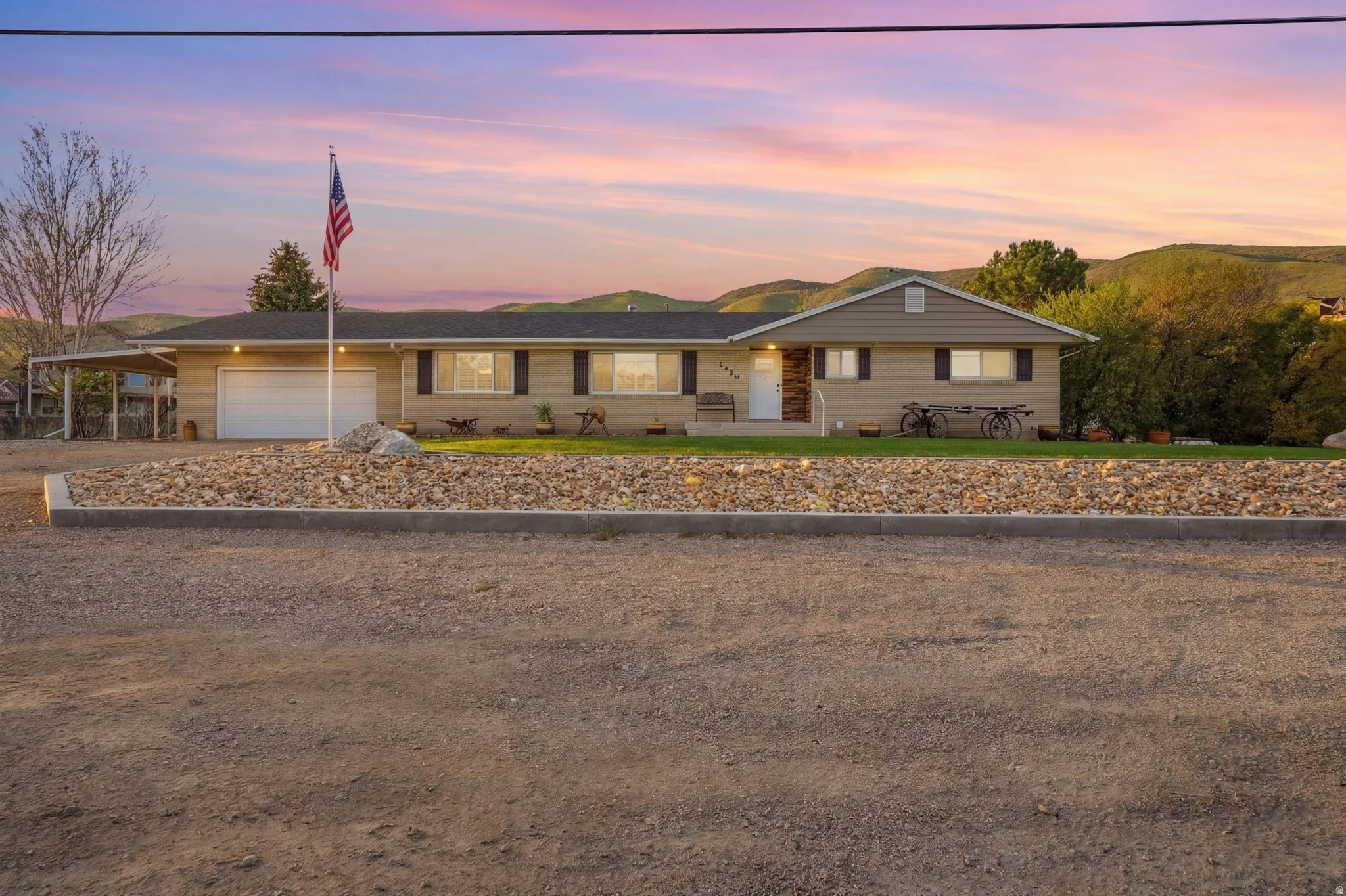 Brick exterior with a detached carport, single garage, and a manicured lawn