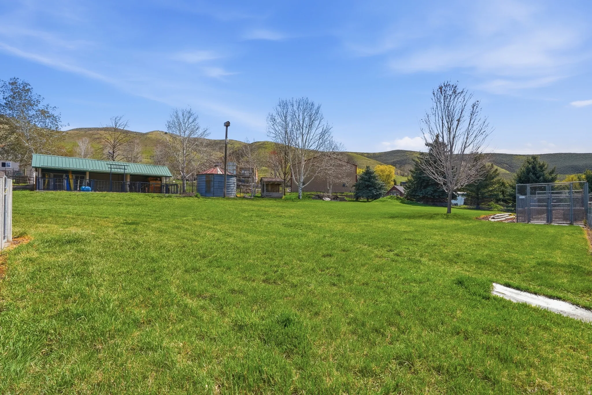 Expansive grassy area with distant rolling hills and a dedicated covered structure