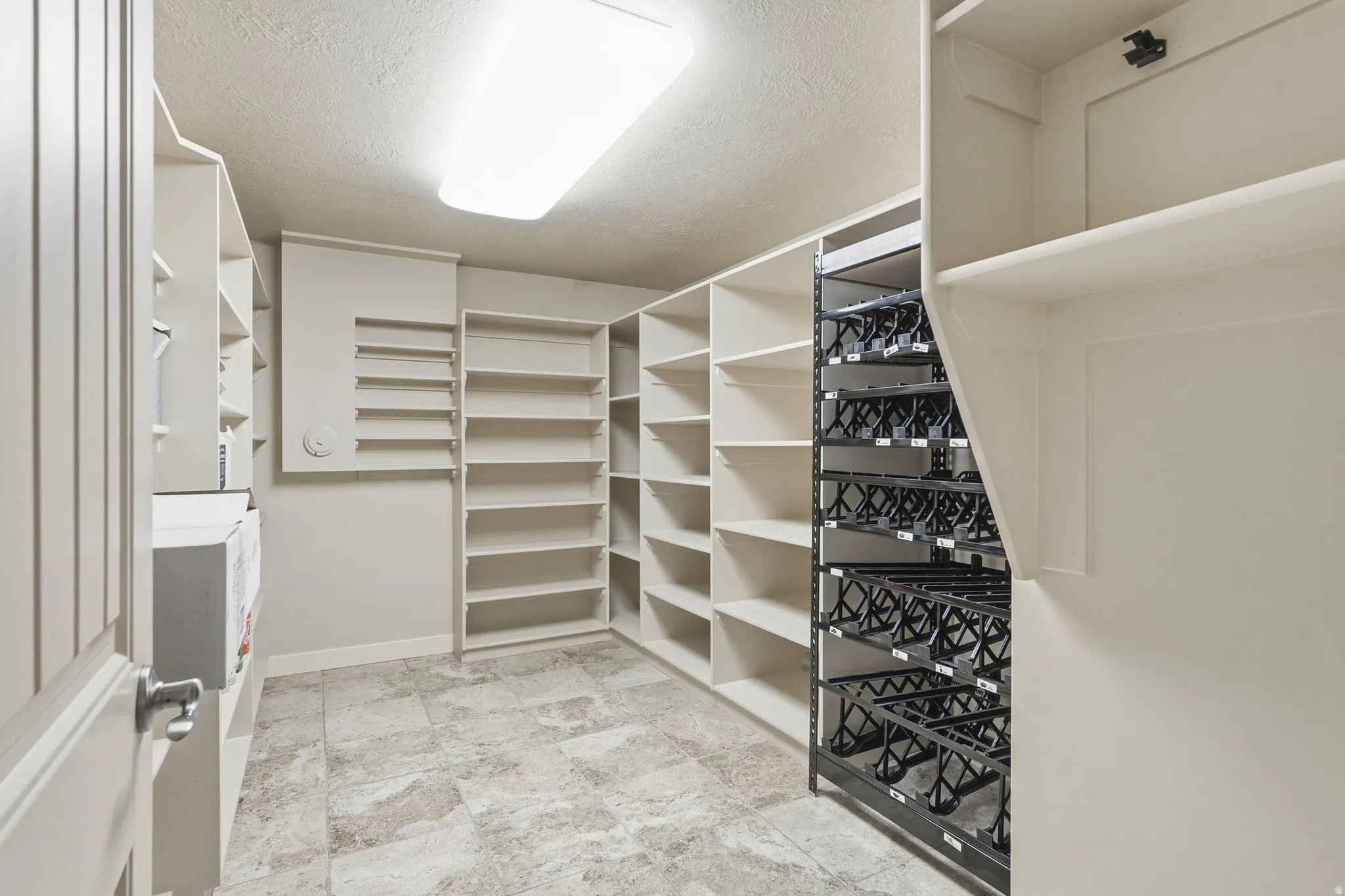 Spacious walk-in pantry with extensive built-in shelving, tile flooring, and integrated wine storage racks