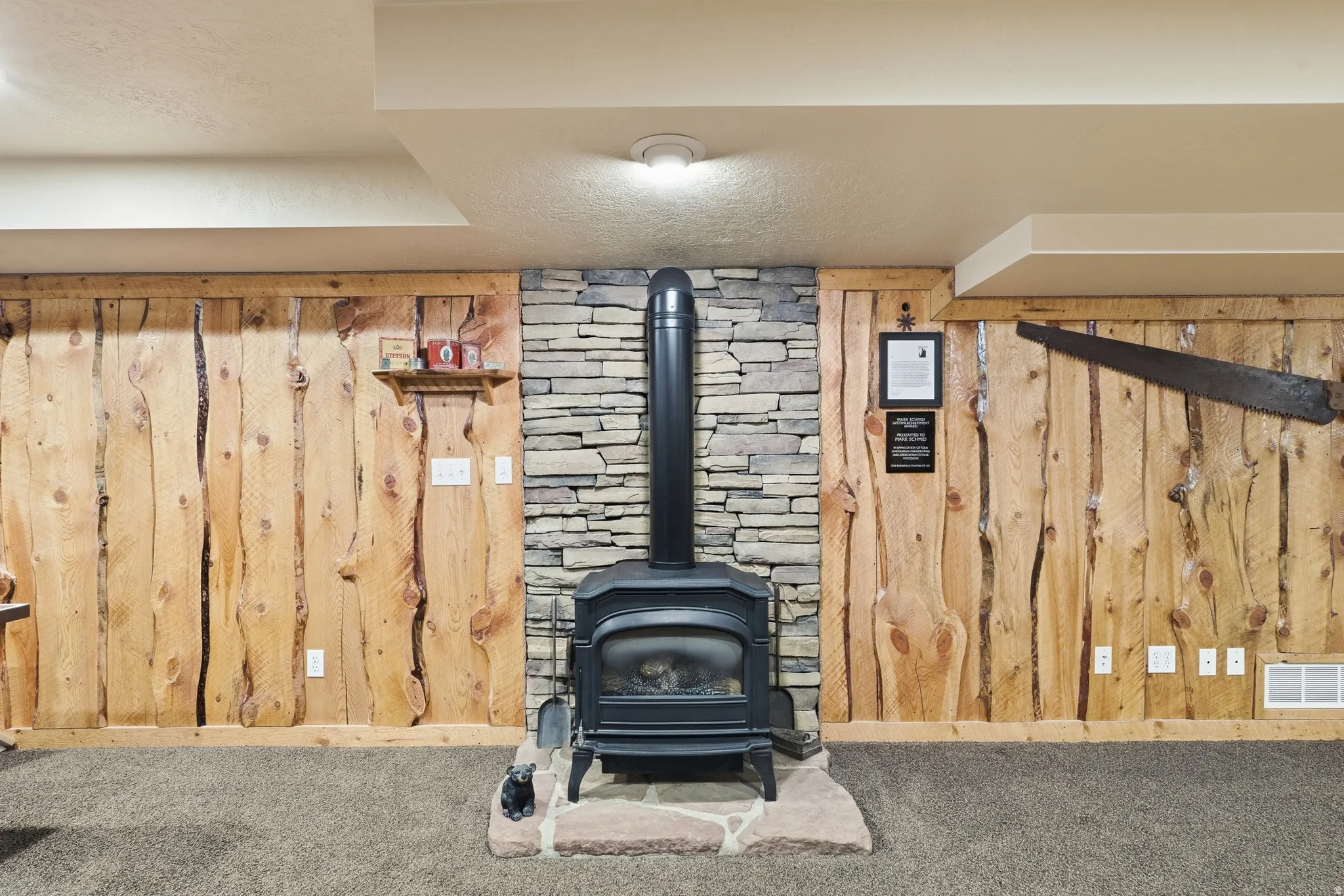 Wood-paneled wall featuring a stacked stone wood-burning stove with a flagstone hearth