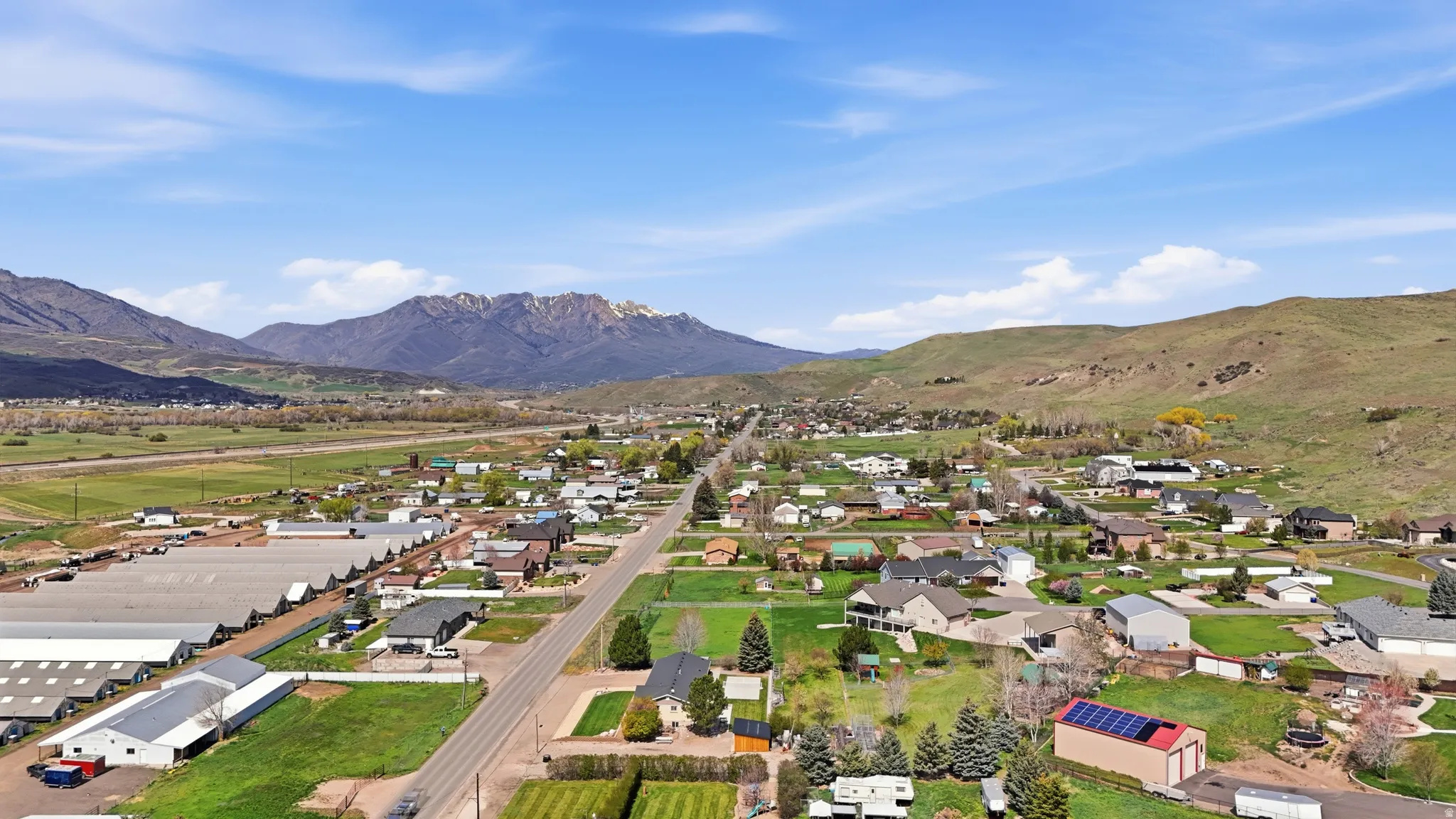 Expansive mountain scenery, residential properties, green landscaping, and open fields with distant buildings