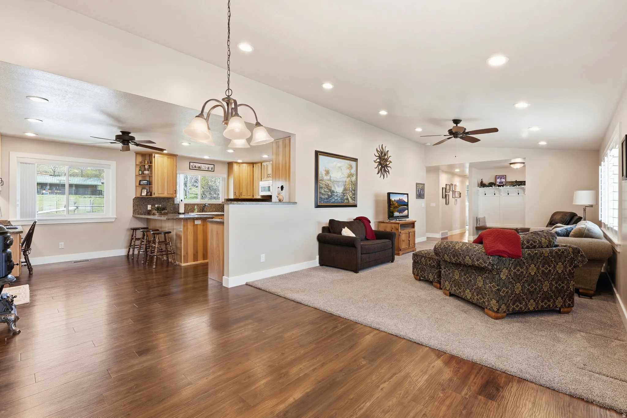 Open-concept living area featuring wood-finish flooring, recessed lighting, and a chandelier