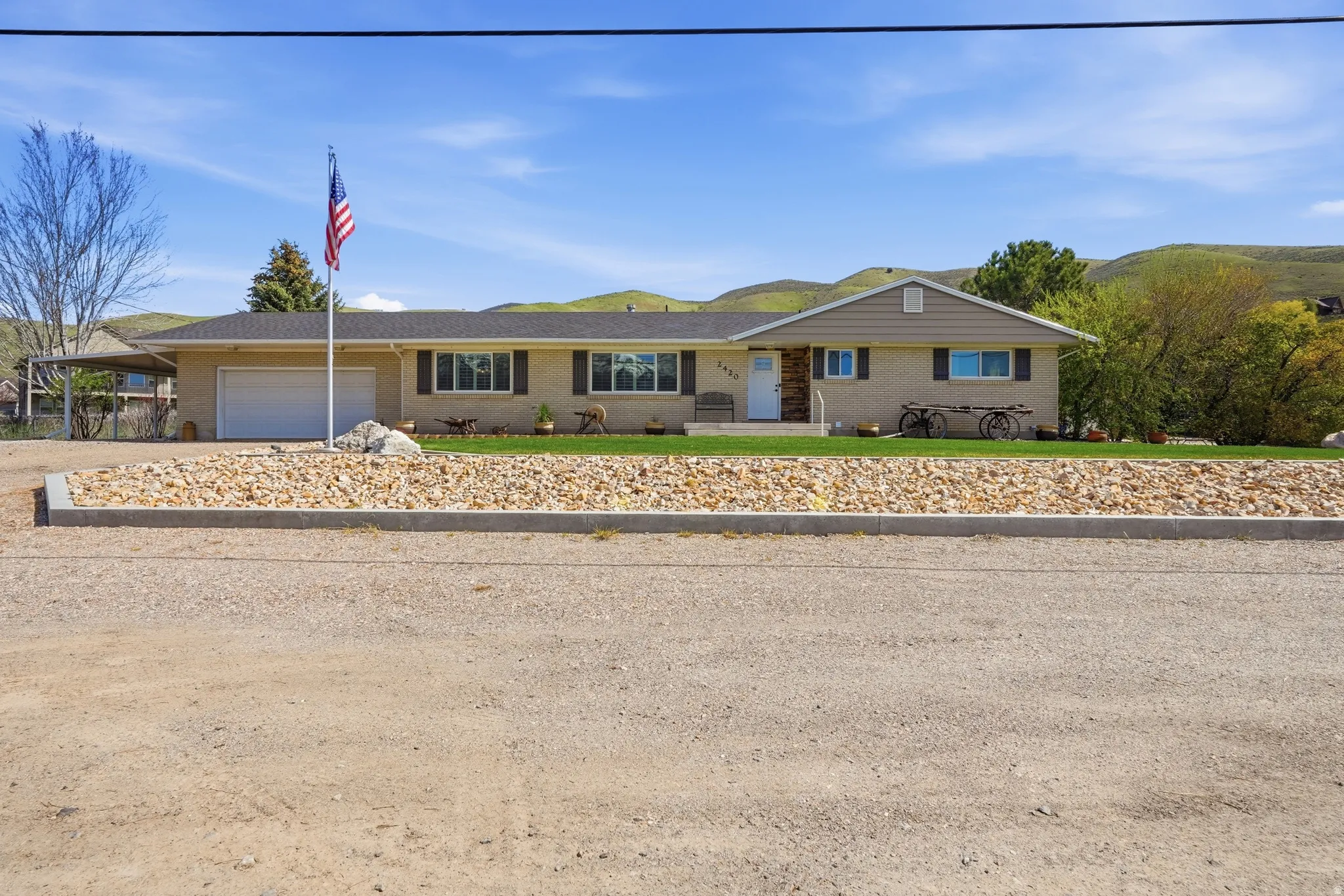 Single-story residence featuring a two-car garage, front lawn, and natural rock landscaping