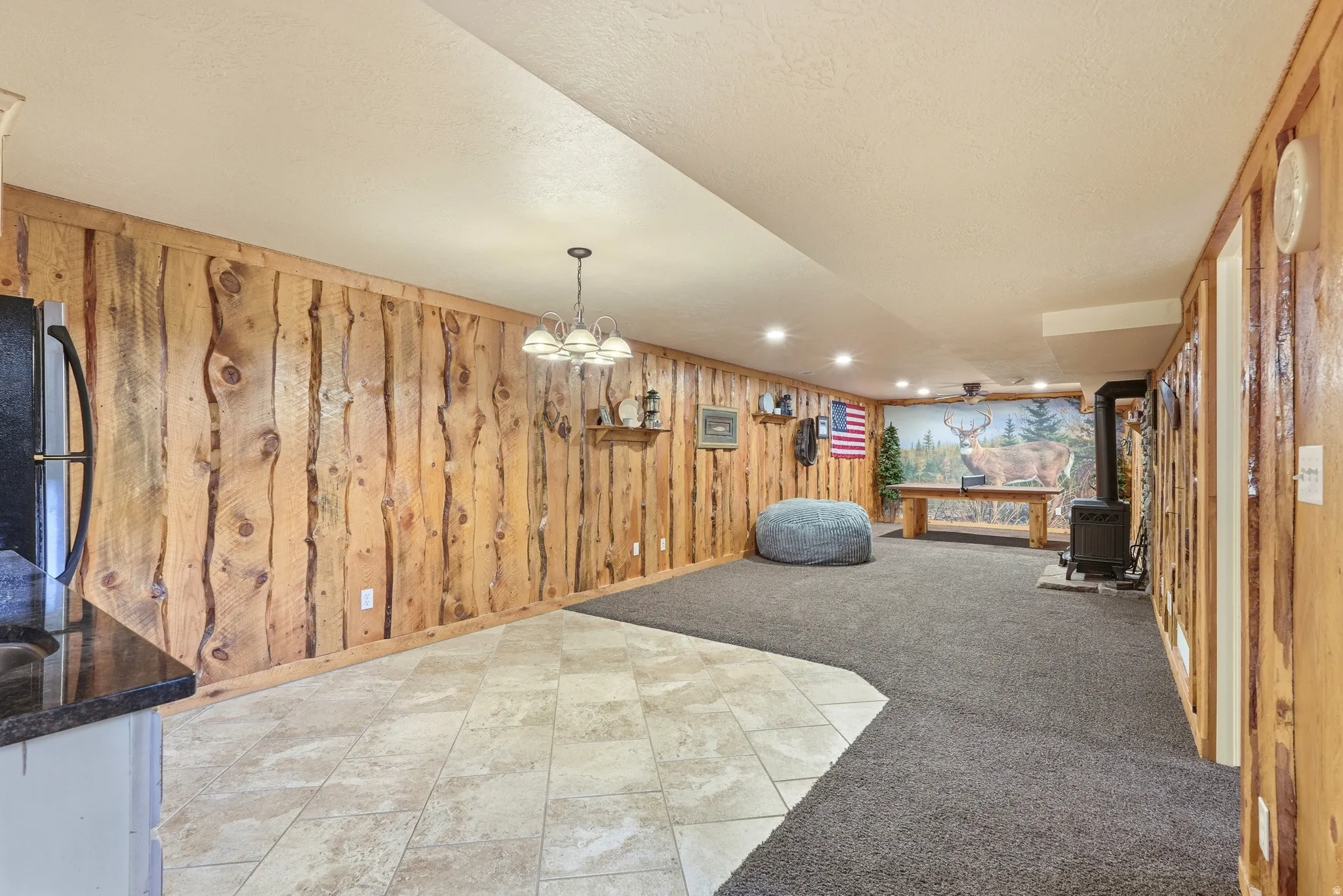 Wood-paneled accent walls, recessed lighting, tile flooring, and dark carpet
