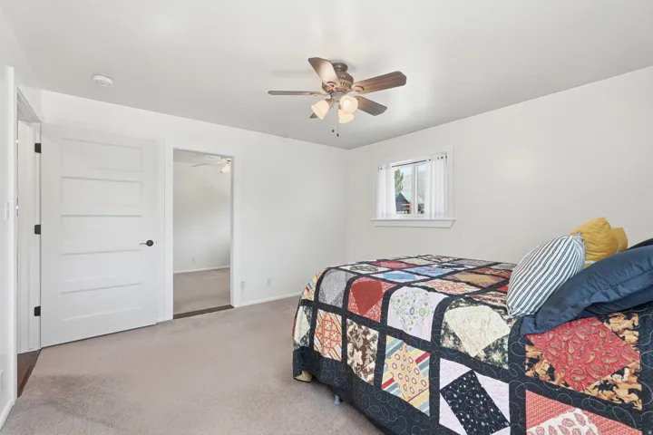 Recessed lighting, ceiling fan with light fixture, window with white trim, white interior doors with black hardware, and neutral carpeting