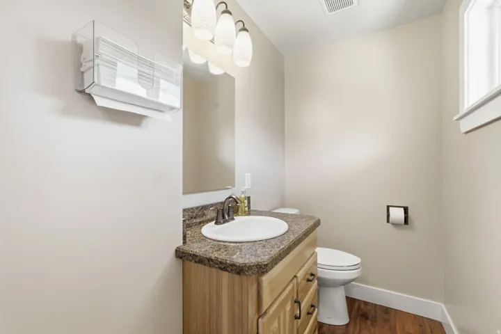Wood-finish flooring with a vanity featuring a built-in sink and a complementary countertop