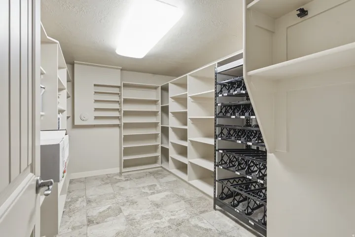 Spacious walk-in pantry with extensive built-in shelving, tile flooring, and integrated wine storage racks