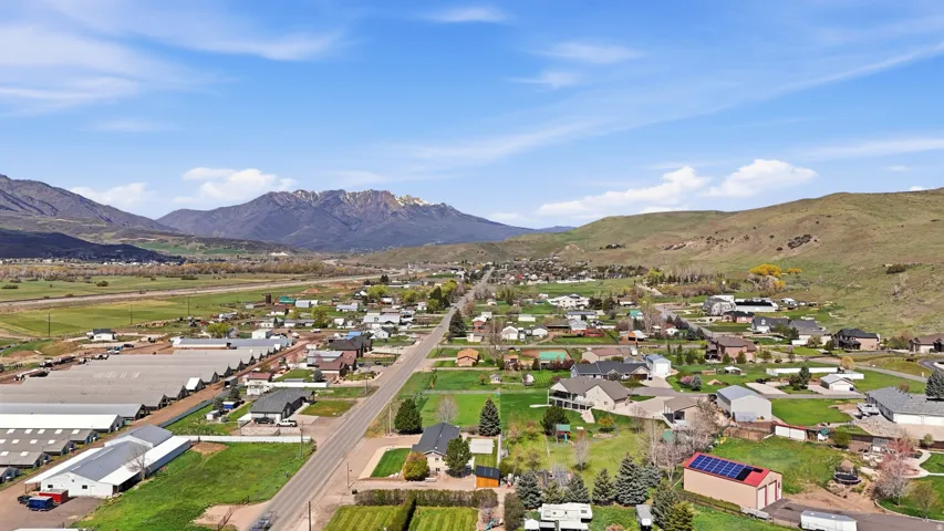Expansive mountain scenery, residential properties, green landscaping, and open fields with distant buildings