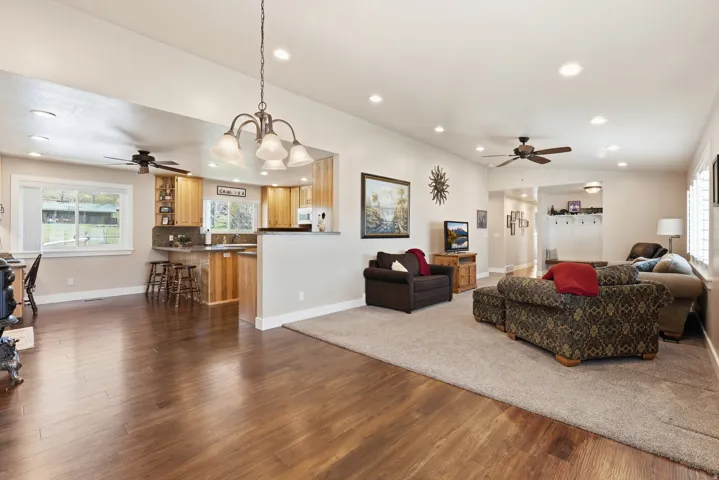 Open-concept living area featuring wood-finish flooring, recessed lighting, and a chandelier