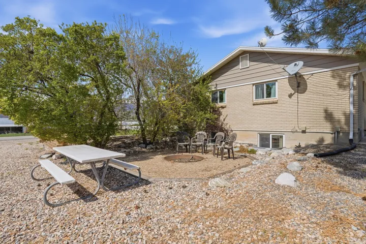 Outdoor living space featuring a gravel patio, built-in fire pit, and mature trees