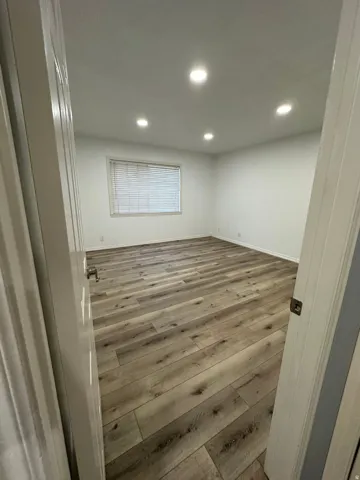 Wood-finish flooring, recessed lighting, white walls, and window blinds