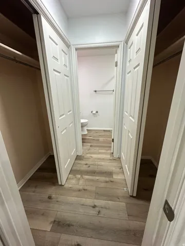 Wood-finish flooring throughout, with panel doors, recessed lighting, and a chrome towel bar
