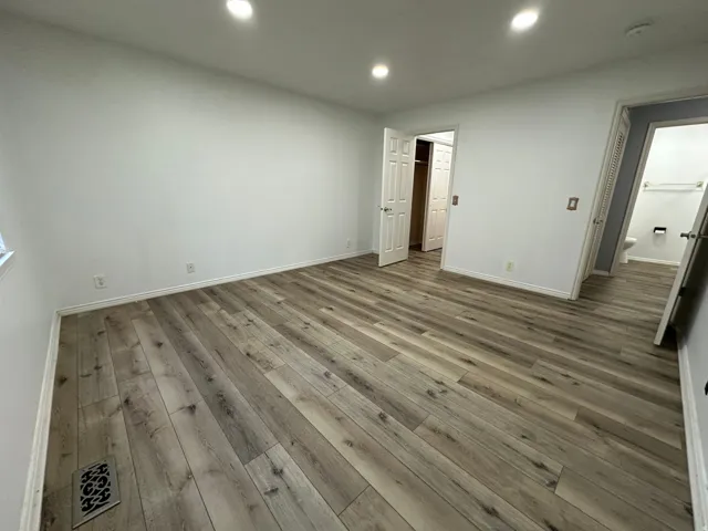 Recessed ceiling lighting, wood-finish flooring, white walls, and white trim