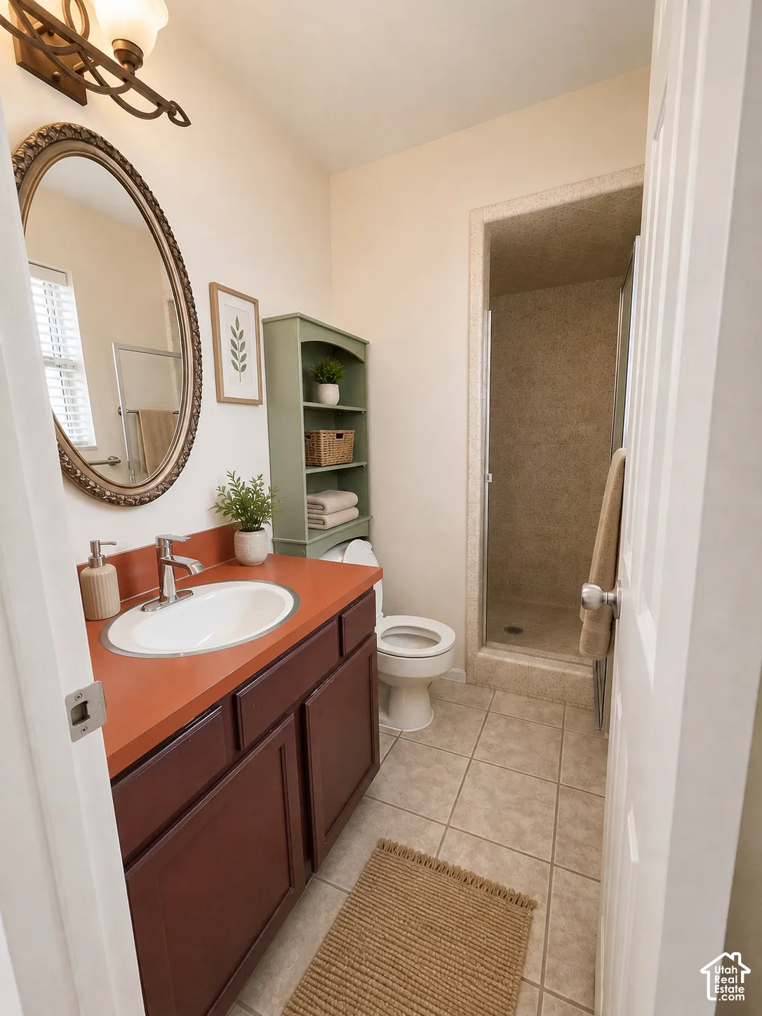 Bathroom featuring a vanity with an oval sink, an oval mirror, an overhead light fixture, a built-in shower, and tile flooring