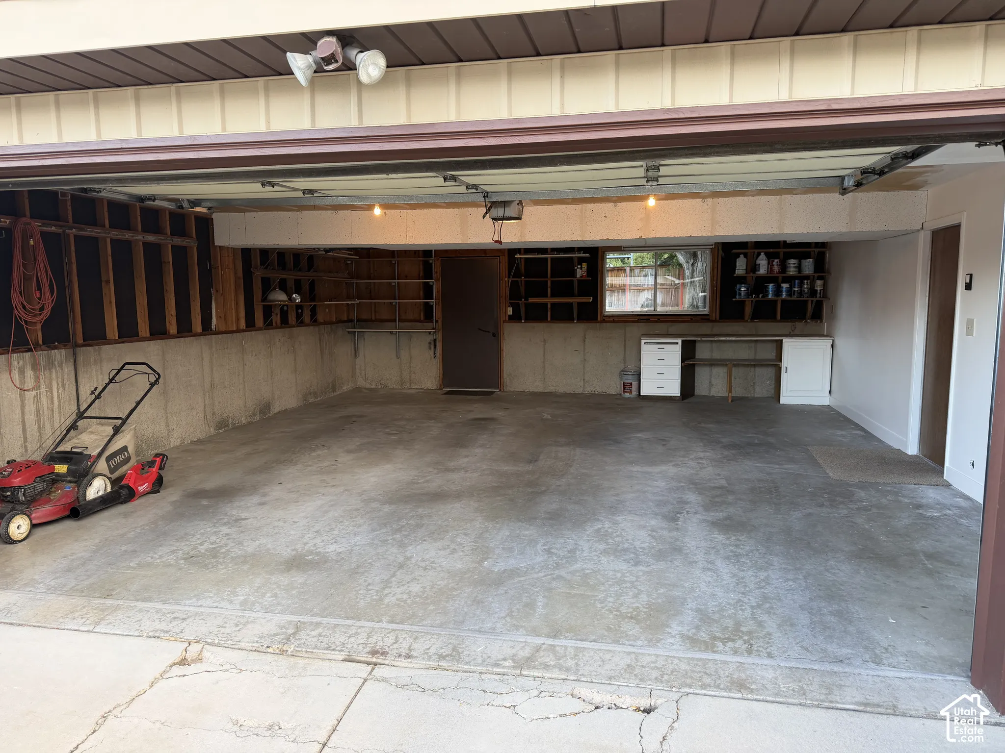 Garage space featuring a concrete floor, built-in shelving, a workbench with cabinetry, and an overhead lighting fixture