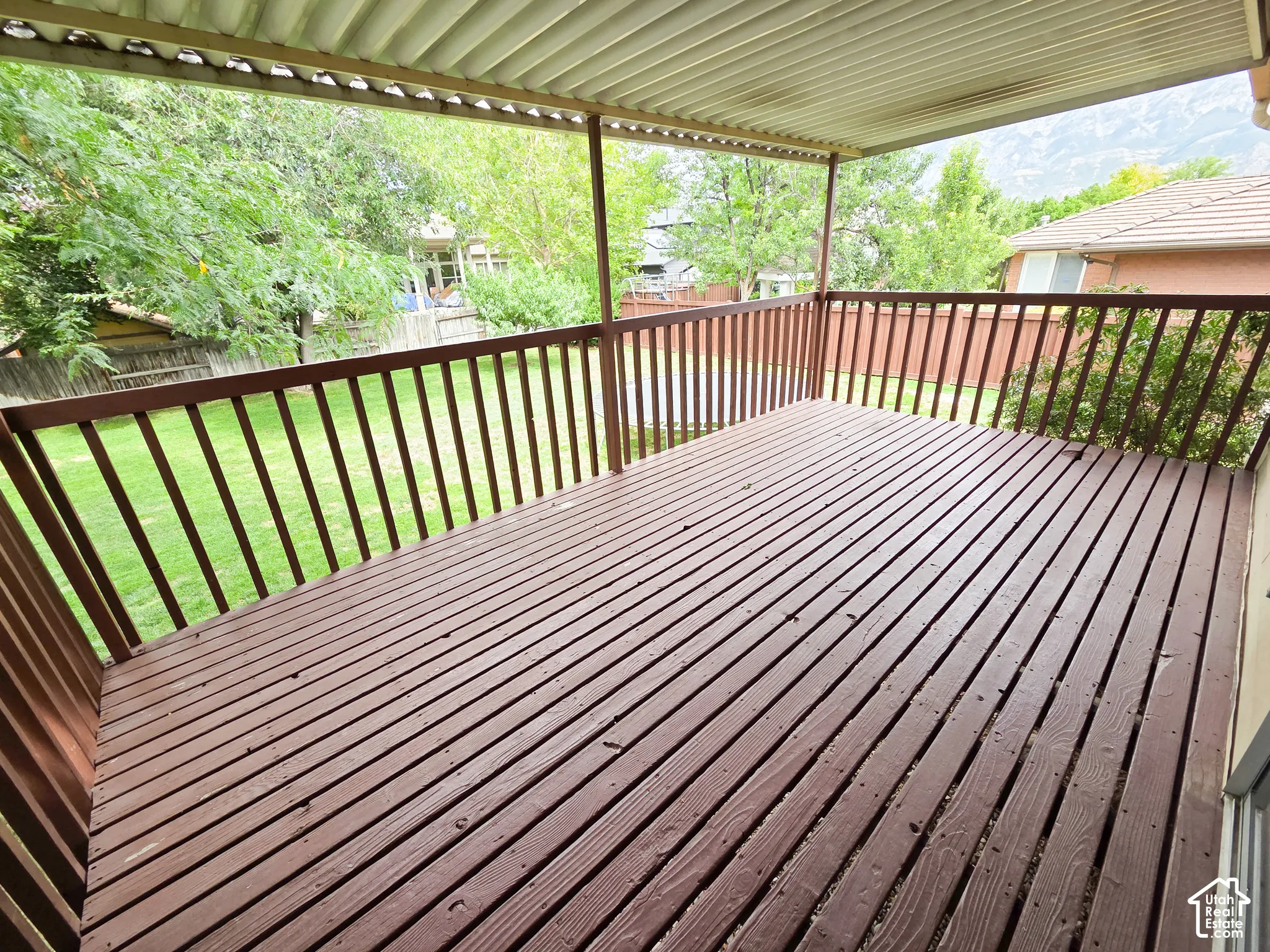 Covered exterior deck with wood-finish decking and wood railing