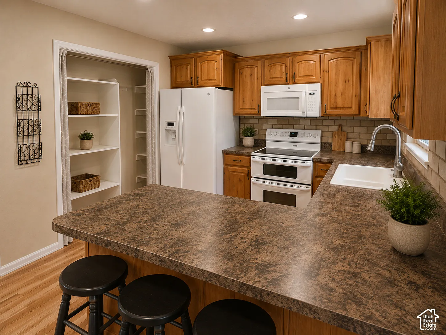 Kitchen featuring wood-finish cabinetry, solid surface countertops, white subway tile backsplash, and a built-in pantry with shelving